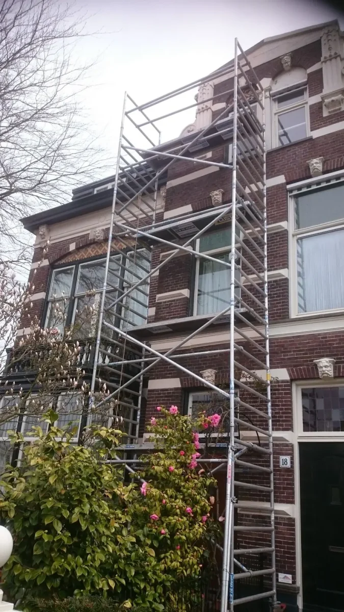 Glaszetter op steiger bij een hoge gevel