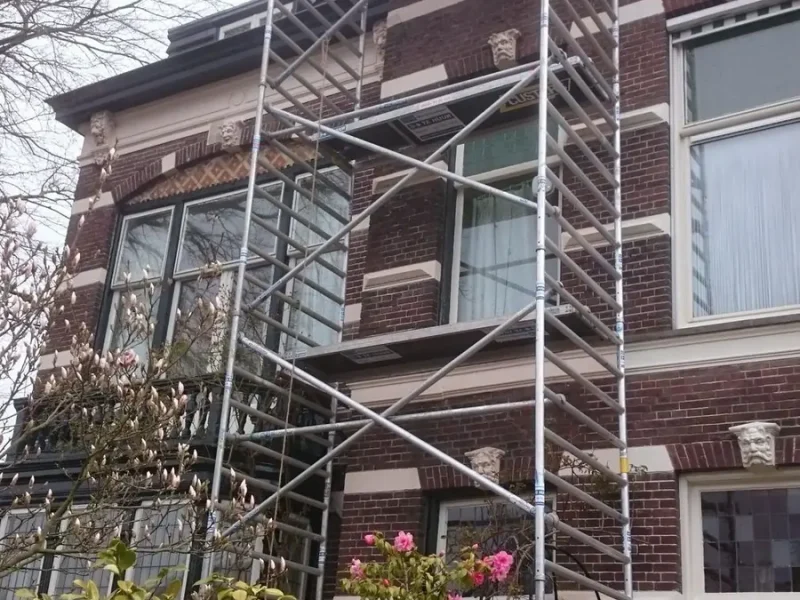 Glaszetter op steiger bij een hoge gevel